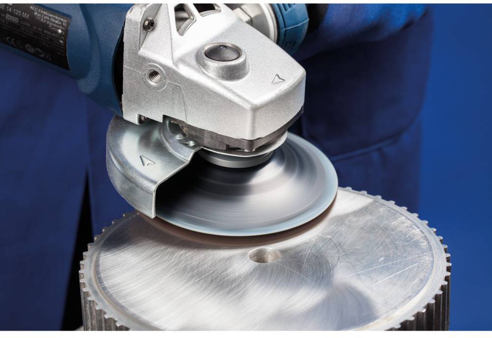 A person is using an angle grinder to polish the surface of a metal plate. Sparks are generated during the grinding process.