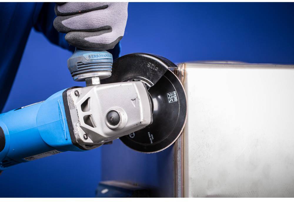 A person is wearing a work glove and using an electric angle grinder to cut metal.