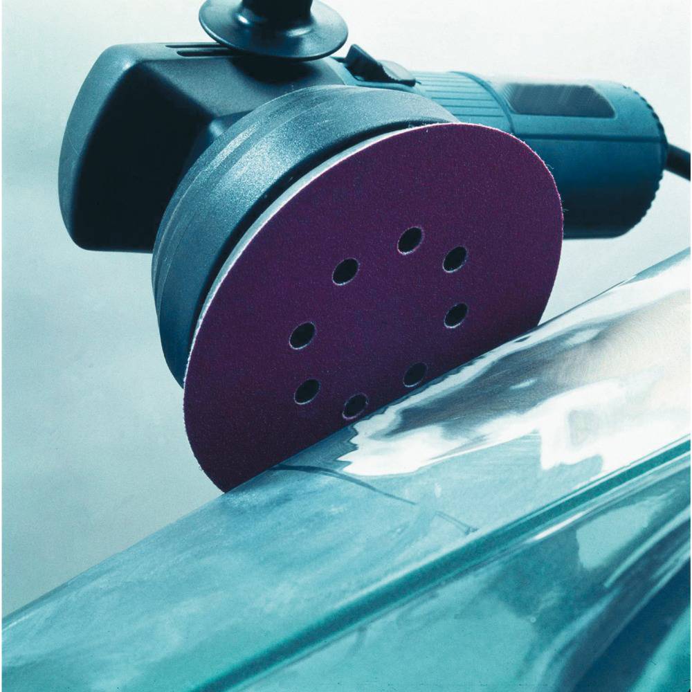 Close-up of a rotating polishing machine with a purple polishing pad, smoothing a mirror-like surface.
