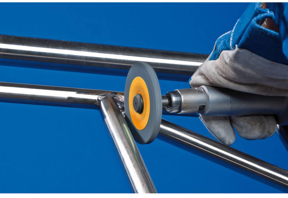 A person is grinding a metal pipe with a grinding machine. Sparks are flying during the grinding process.