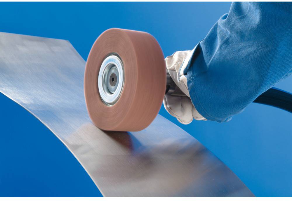 A person is grinding a metal sheet with a grinding machine.