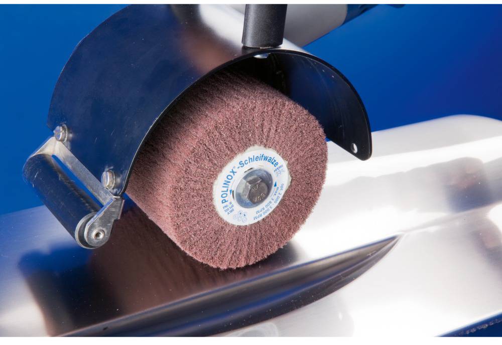 A rotating grinding wheel is machining a metal surface. The grinding wheel is fitted with a protective cover.