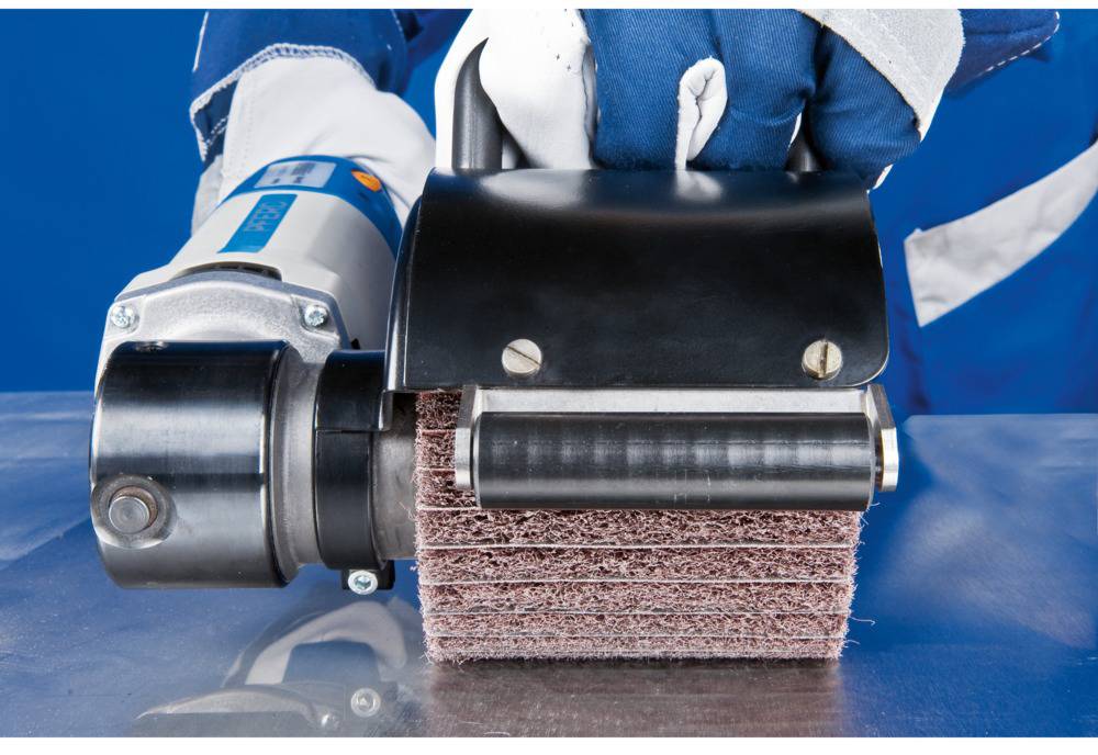 A person is holding a professional grinding machine with a rotating brush, ready to process a metal surface.