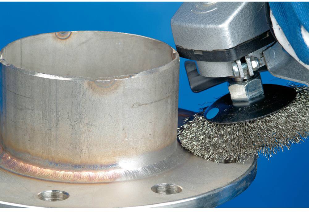 A metal pipe is being processed with an electrical wire brush. The surface of the pipe is partially ground.