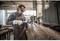 A man in protective clothing and safety glasses is welding a large metal cylinder in a workshop.