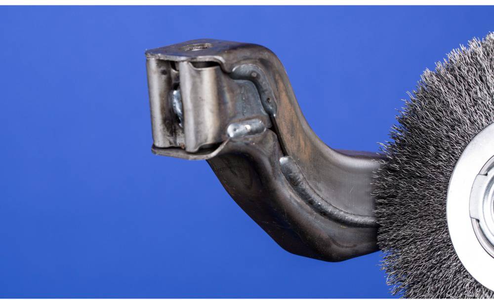 'Close-up of a wire brush with a metal handle against a blue background, showing the detail of the brush head and bristle structure.'