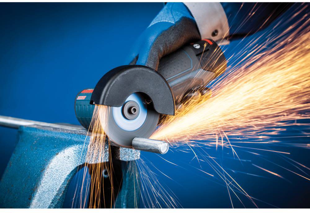 A person is cutting a metal rod with an angle grinder, sparks flying. The image conveys the use of power tools.