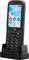 A mobile phone with buttons, standing on a charger. The screen displays the time 09:30 and the date Monday, 27 April.