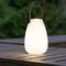 A portable, glowing lantern sits on a wooden table outdoors. It has a curved shape and a handle.