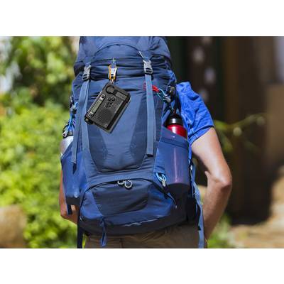 A person is carrying a large, blue rucksack with a black camera attached to the side. Trees and buildings can be seen in the background.