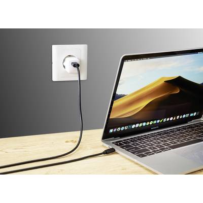 A laptop is connected to a plug socket with a charging cable. The screen displays a desert landscape.