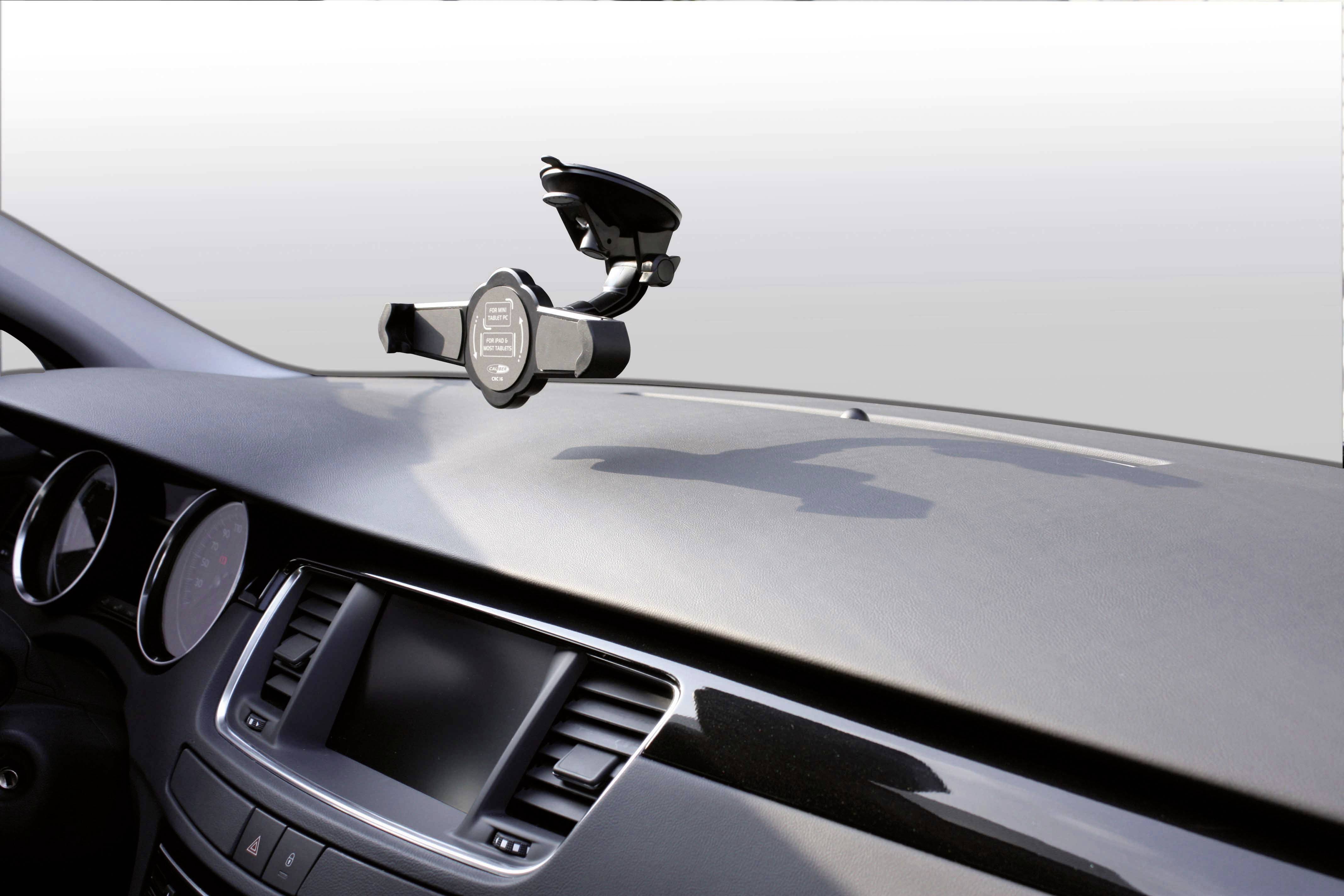 A mobile phone holder is mounted on the dashboard of a car, ready for use for navigation or calls.