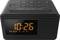 A digital alarm clock with an LED display shows 10:26. Buttons on top for functions such as snooze and volume.
