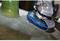 A angle grinder is machining a fibreglass surface, an abrasion tool with a blue grinding pad glides over the material.