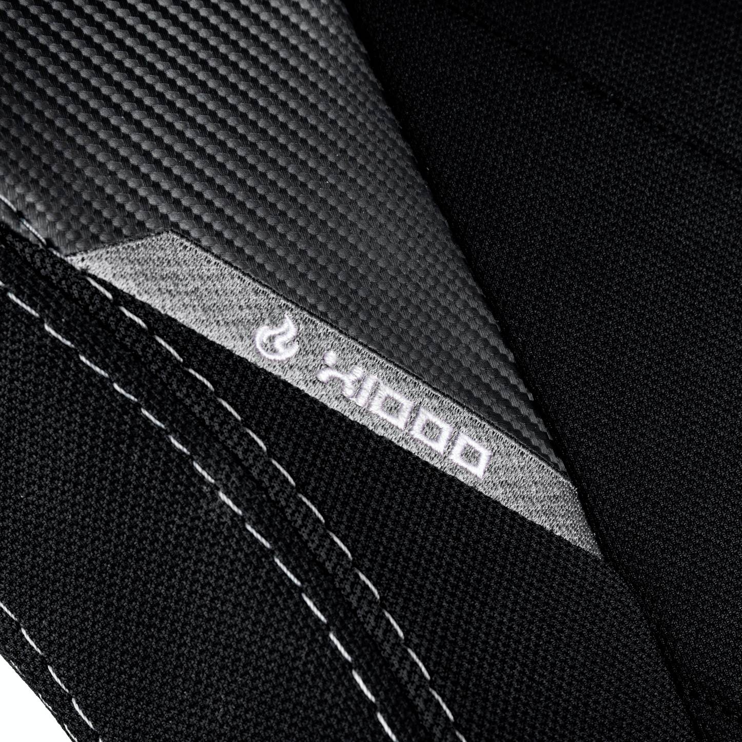 Close-up of black, textured fabric with grey stitching and a small, white flame symbol next to the inscription 'x1000'.