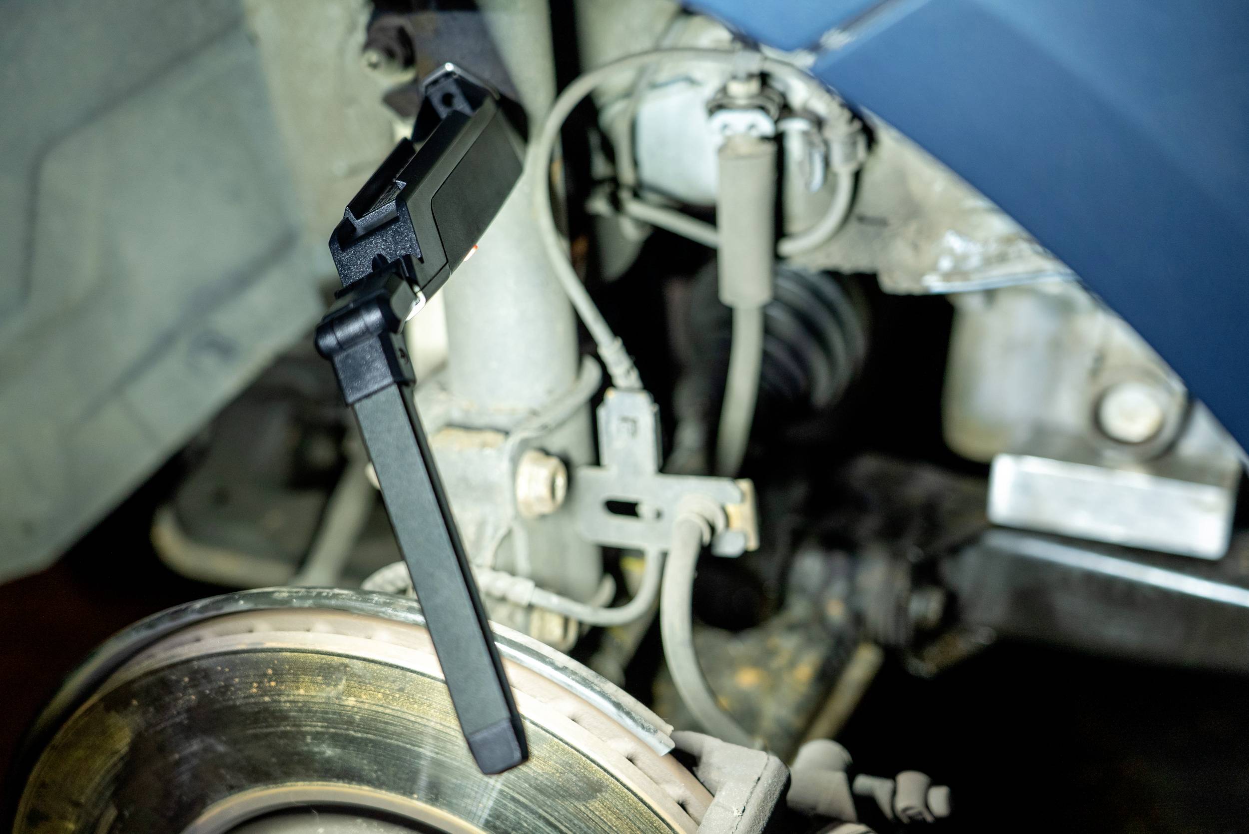 A car sensor is mounted on a vehicle wheel and monitors the braking system. The sensor is black, the car is blue.