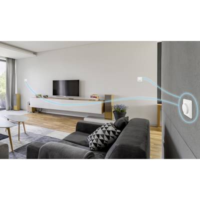 A modern living room with a sofa, television mounted on the wall, and a digital thermostat on the right wall. A blue cable indicates the connection.