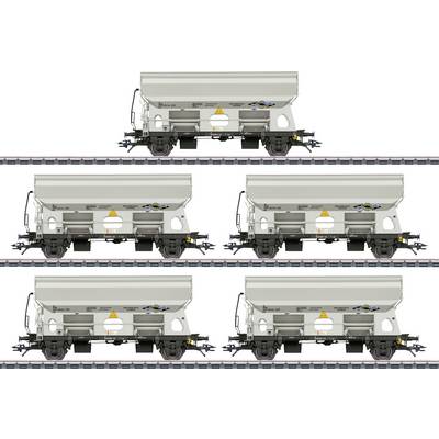 Five light grey freight carriages on tracks in two rows, each with a yellow warning patch, positioned at regular intervals.
