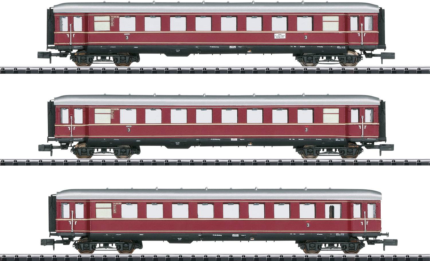 Three rusty-brown railway carriages on parallel tracks. Each carriage has a different number of windows and doors.