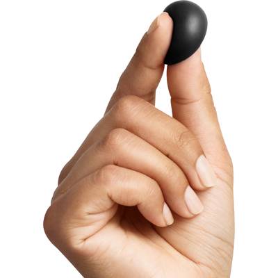 A hand holds a small, black pill between thumb and index finger.