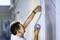 A person carefully applies blue masking tape to a wall to mark out an area for painting.