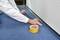 A person is laying blue carpet in a room and using yellow tape to secure the edges along the wall skirting.