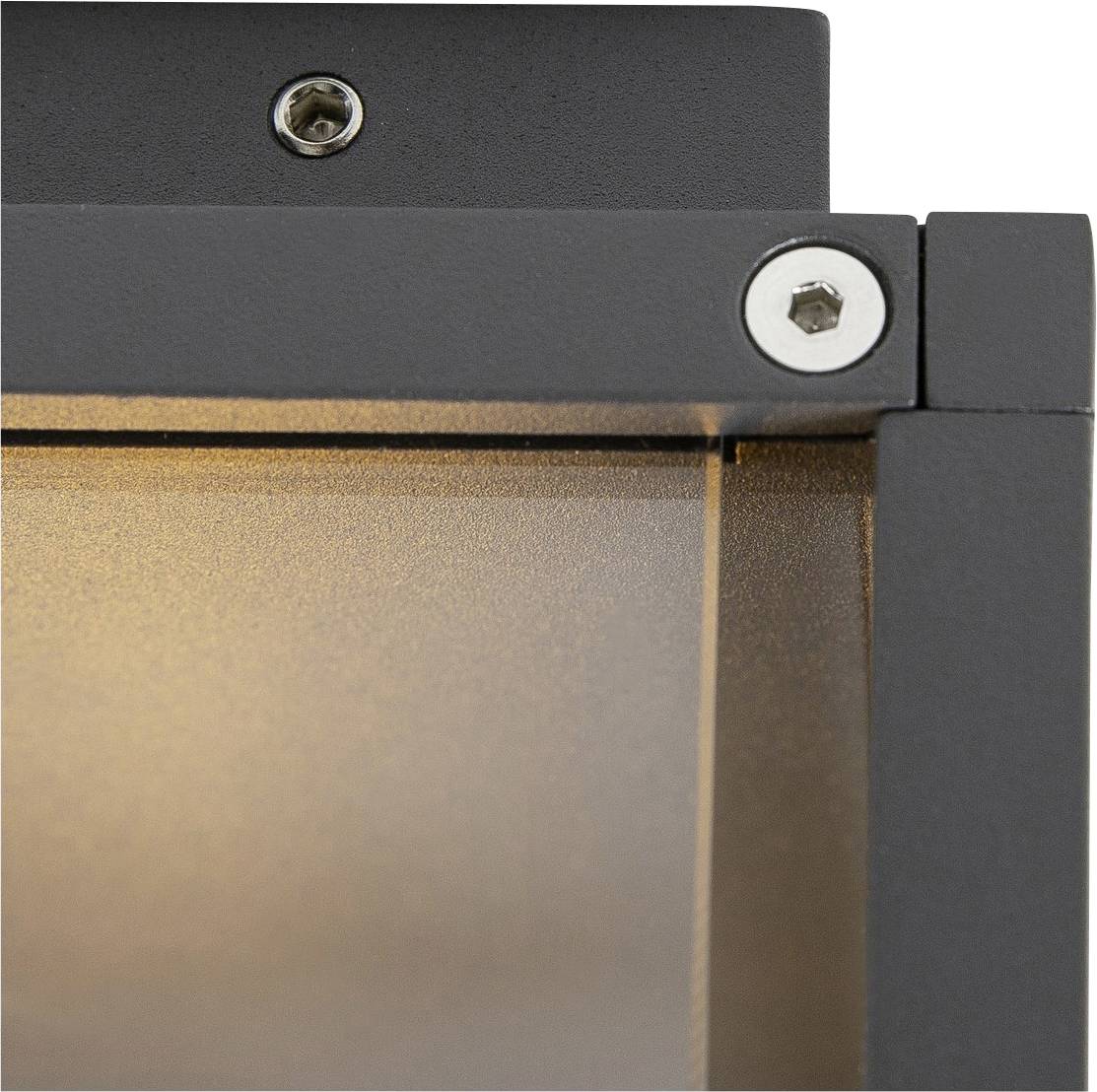 Close-up of a black and grey metal frame with visible screws at the corners and a slightly illuminated surface in the background.