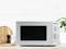 Microwave on kitchen worktop, surrounded by wooden chopping board and pepper mills, against a white tiled wall.