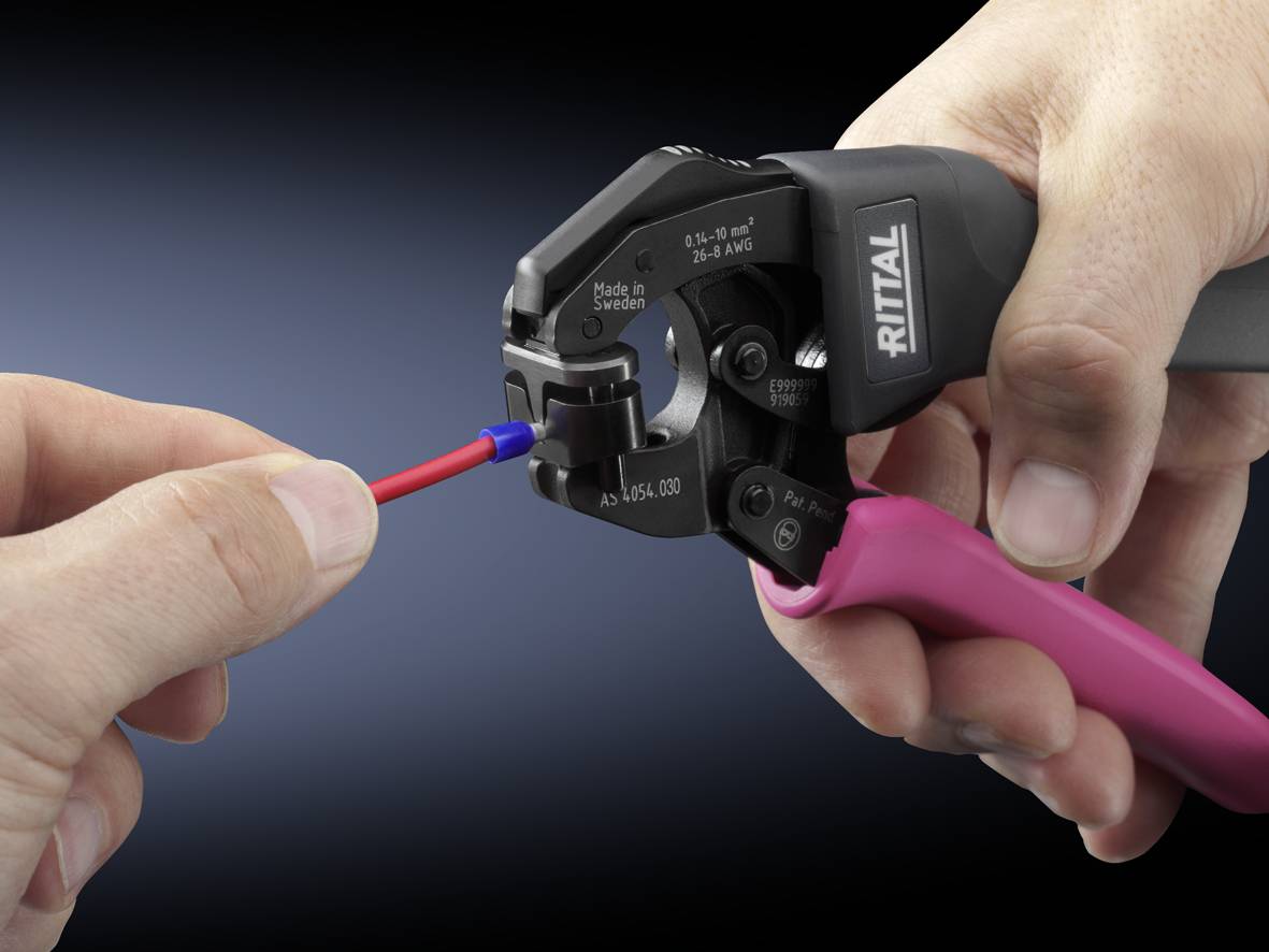 A hand is holding a Rittal wire stripper while the other hand is inserting a red cable.