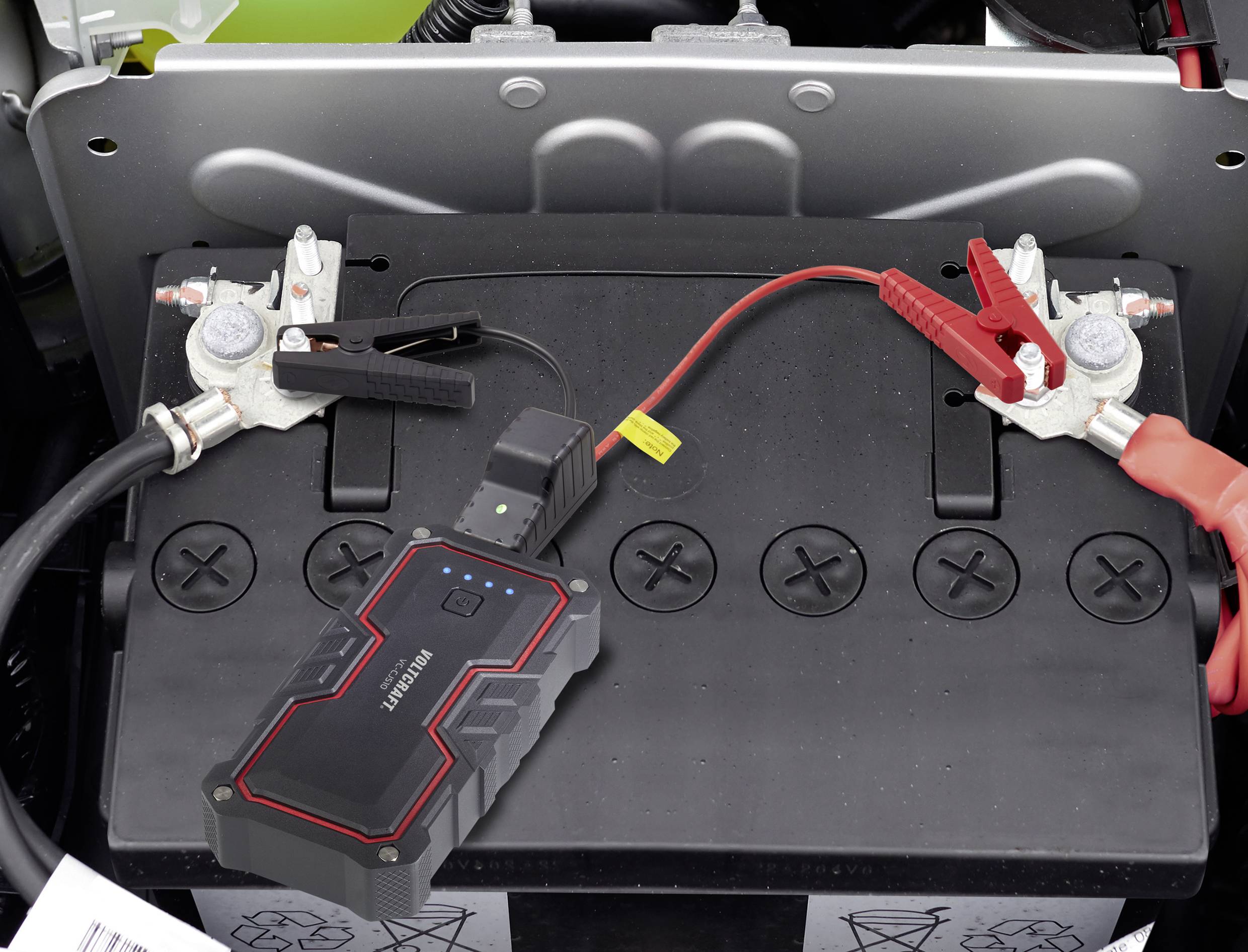 Car battery connected to jump starter. A black jump lead is attached to the negative terminal, a red one to the positive terminal.
