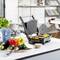 On a kitchen worktop, an open grill with grilled vegetables can be seen. In front of it lie additional vegetables and kitchen utensils.