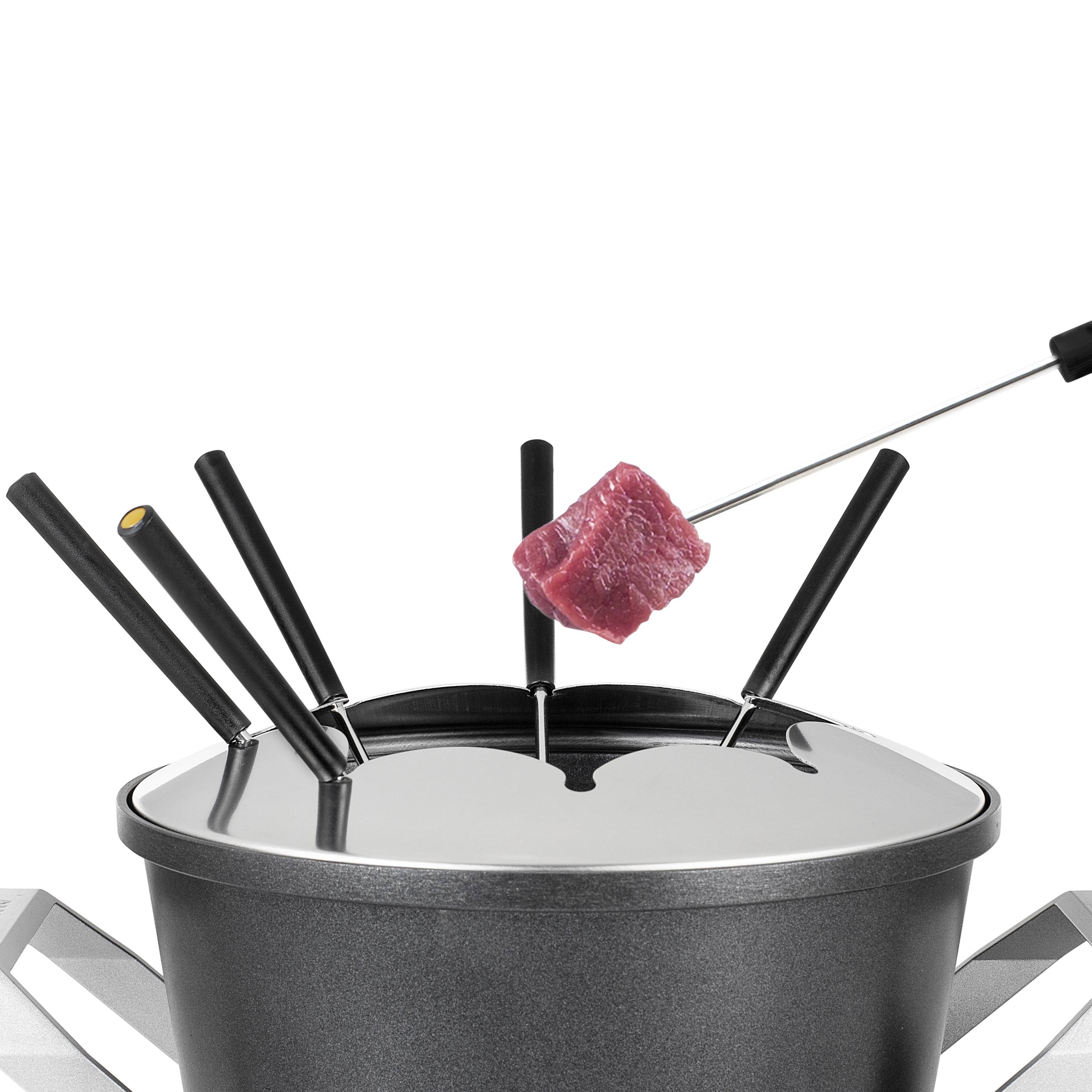 Fondue pot with a piece of meat on a fork, placed on a metal grid table. Meal prepared for cooking in the fondue.