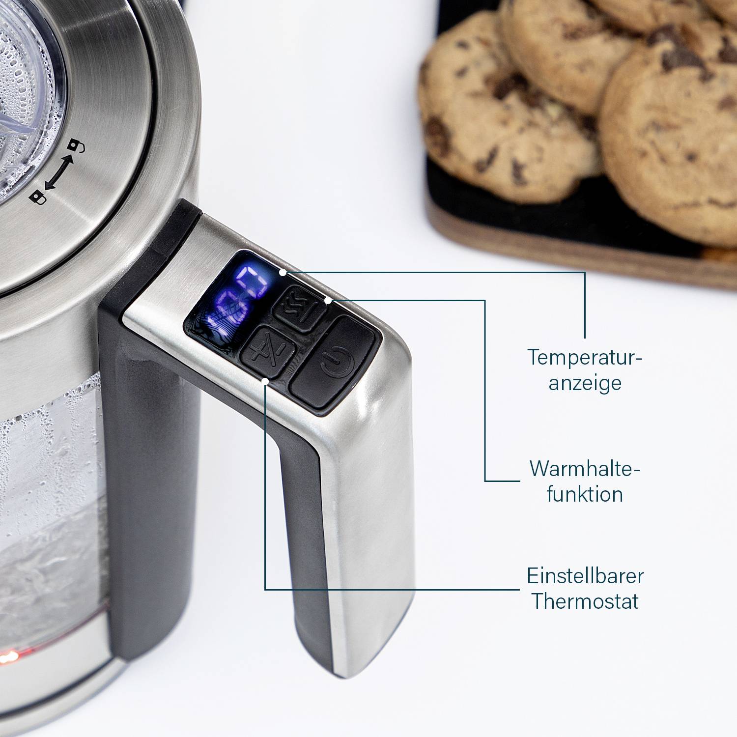A kettle with a digital temperature display and adjustment buttons on the handle shows the current temperature. In the background, a plate of biscuits.