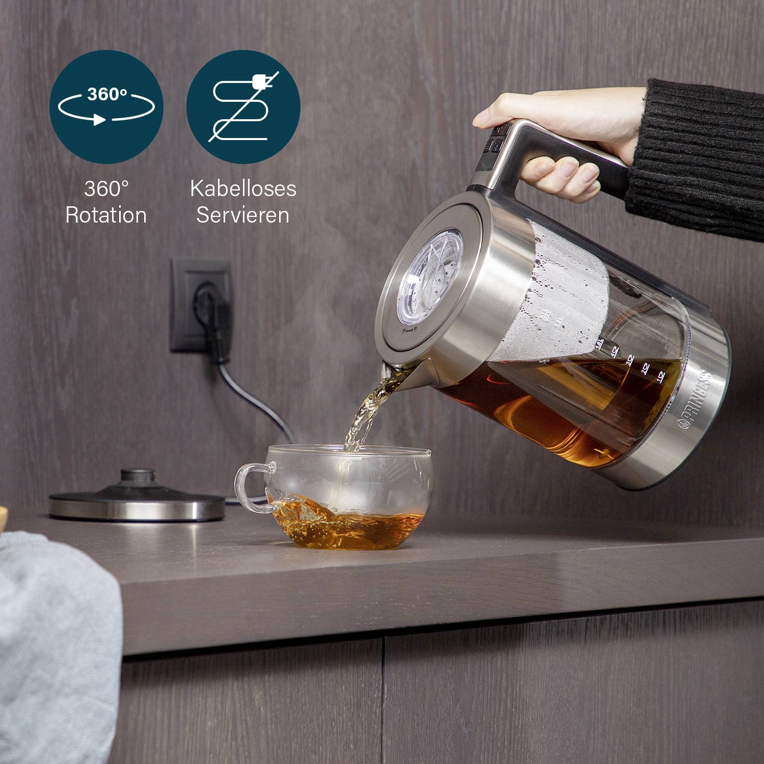 A hand pours tea from a cordless kettle into a cup. The kettle has 360-degree rotation.