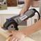 A person is working with an electric power tool to cut wood precisely. Focus on the tool and piece of wood.