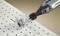Dremel tool cuts a round hole in a white perforated board, generating sawdust. Close-up of the process.