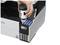 A hand is refilling ink into a printer. The printer has four ink tanks in the colours Black, Yellow, Magenta and Cyan.