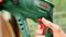 A hand is holding a green Bosch hammer drill 'PBH 2500 RE', which is used for powerful drilling and chiselling.