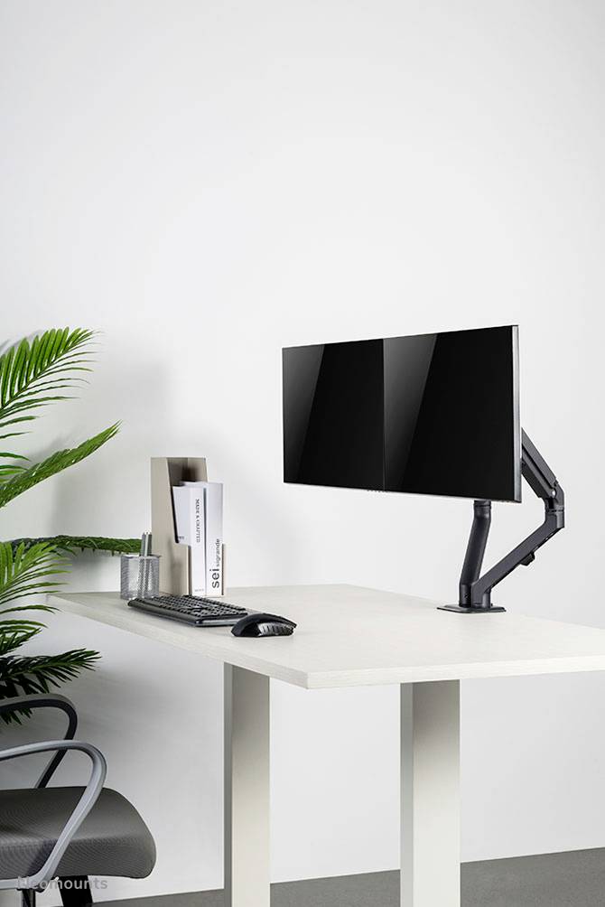 Modern desk with ergonomic monitor arm, keyboard, mouse and stylish decor; minimalist office setup.