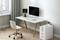 A bright, modern office with a white desk, computer screens, a white wheeled office chair, and a small plant.