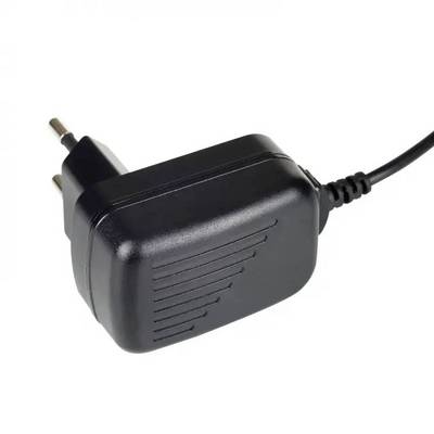 A black power adaptor with two metal pins and a cable, typically used for electronic devices.