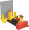 A LEGO model depicts a factory scene with a conveyor belt, robotic arms, and cables. A grey wall is visible in the background.