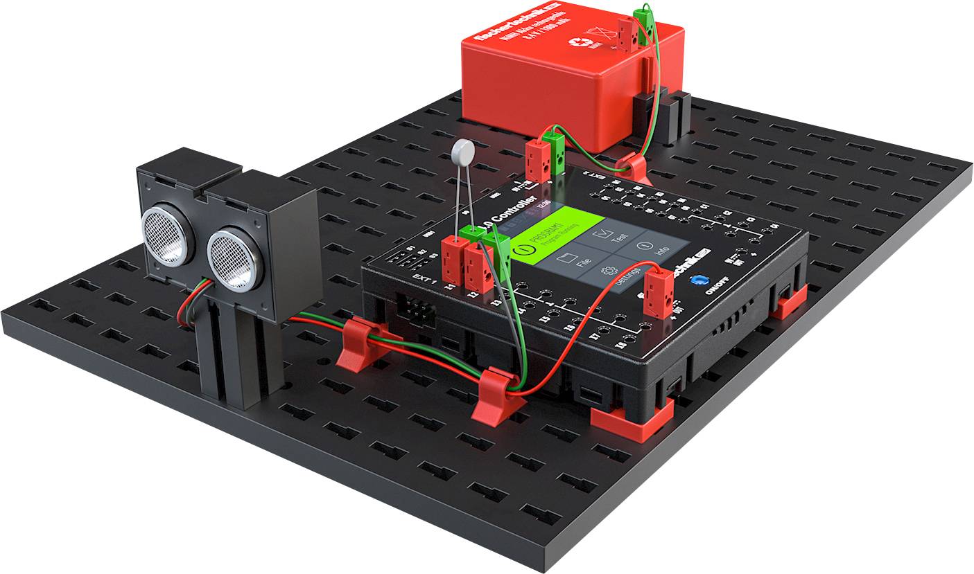 An electronic assembly on a black board with red and black components, interconnected by green cables, sensor-like and battery-powered.