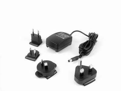 Black power adapter with multiple interchangeable plugs for different socket types, cable coiled.