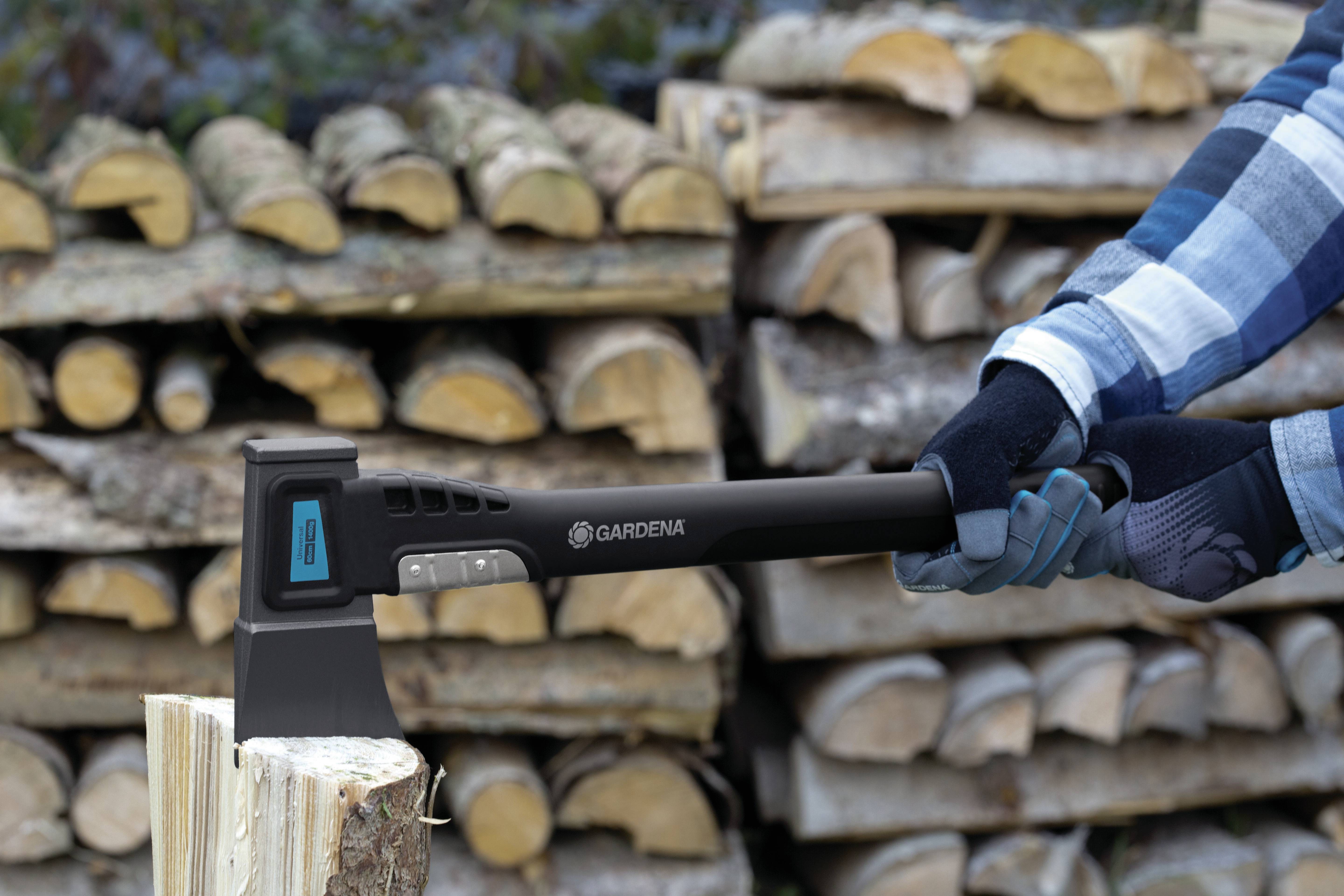 A person is splitting wood with an axe. Stacked logs can be seen in the background.