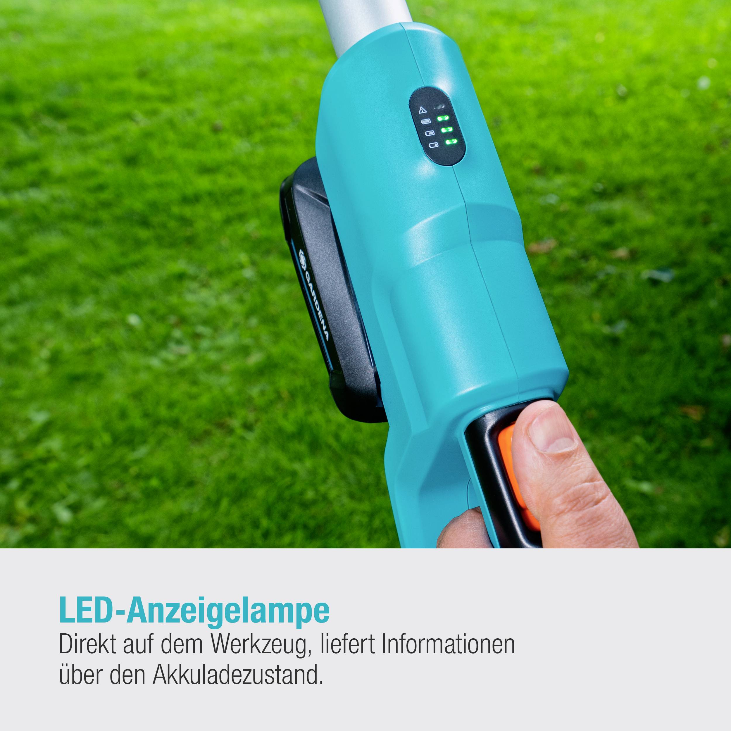 'LED display lamp above the tool, provides information about battery status.' A hand grips the handle. Lawn in the background.
