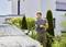 A man is cleaning a car with a pressure washer in the garden in front of a modern house.