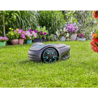 A robotic lawnmower is autonomously mowing green grass in a garden, with colourful potted flowers in the background. It is raining lightly.