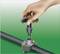 A hand is mounting a vertical valve onto a pipe with a clamping disc at a pipe connection.