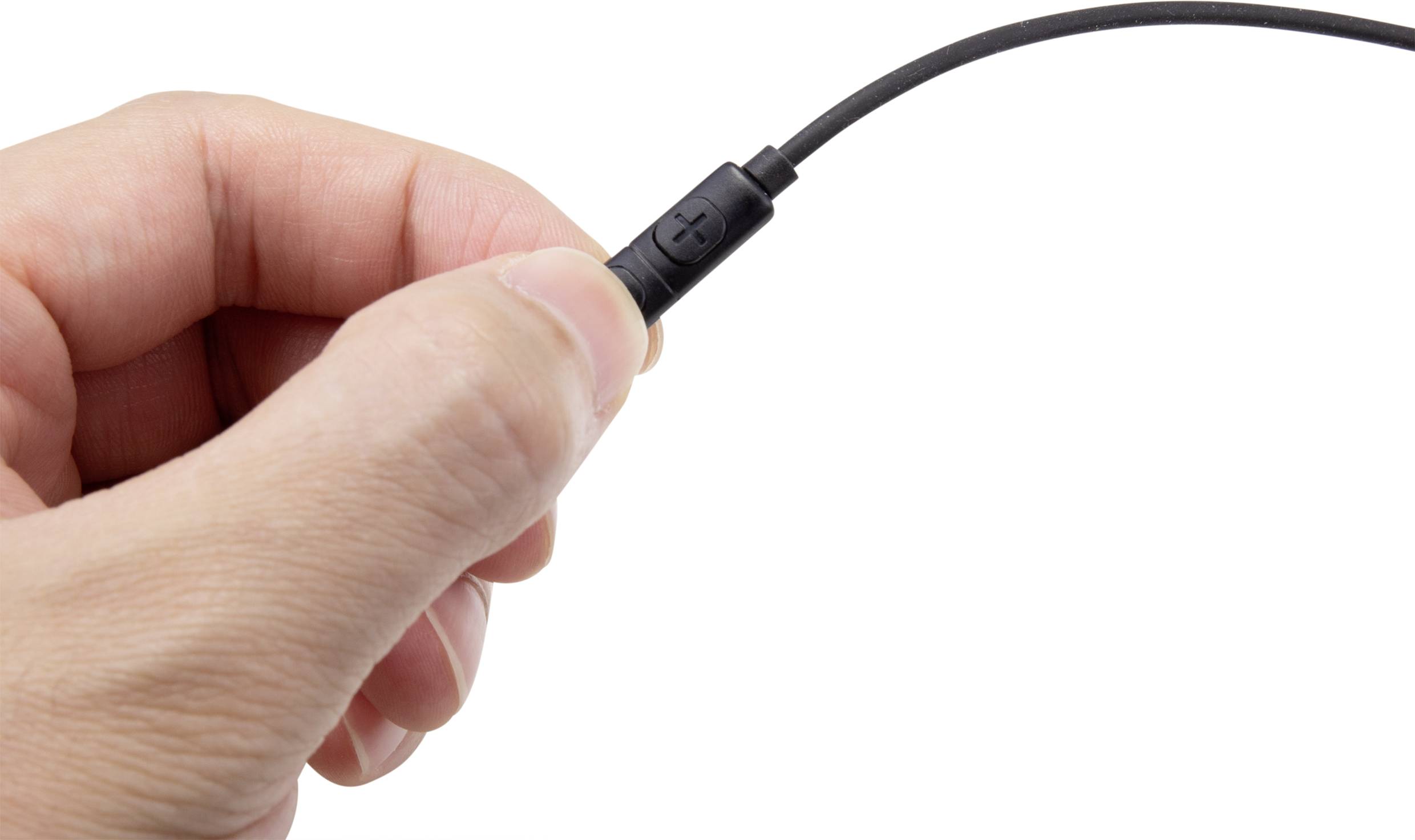 'A hand holds a black audio cable connected by a plug.'